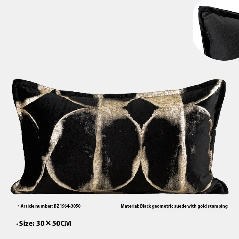 Black and gold abstract pattern decorative square and waist pillow cushions on a grey sofa.