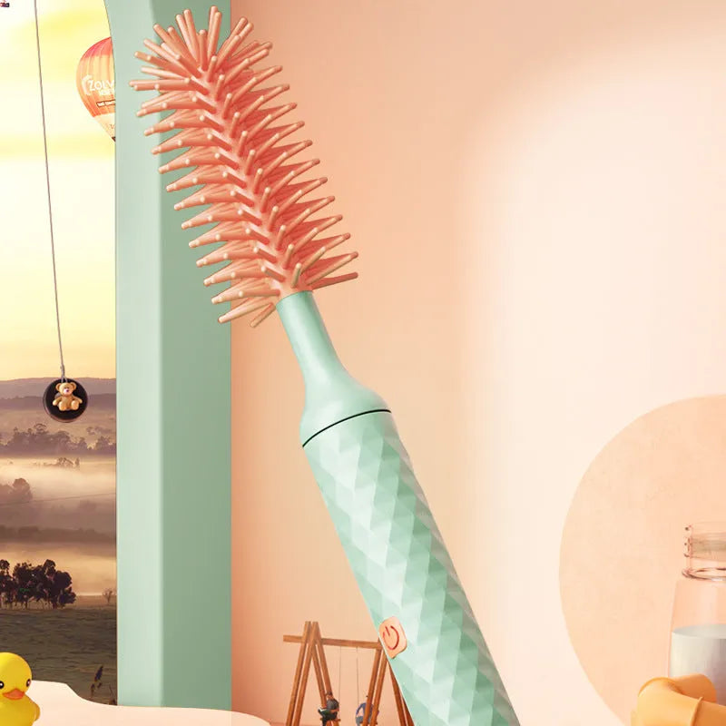 Pink and green electric rotating bottle cleaning brush with silicone bristles on a white background.