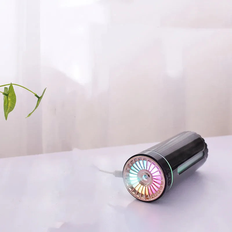 Black wireless USB car humidifier with colourful LED lights on a desktop next to a cup holder.