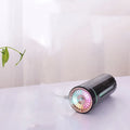 Black wireless USB car humidifier with colourful LED lights on a desktop next to a cup holder.
