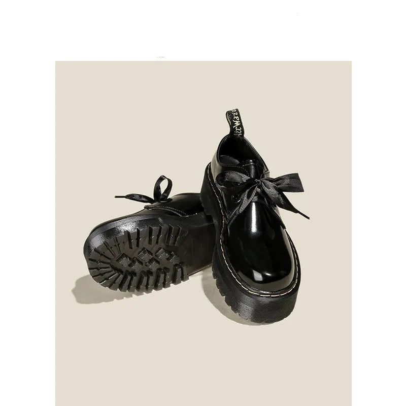 Black women's thick soled lace-up shoes with a cross-strap and ribbon detail on the front.