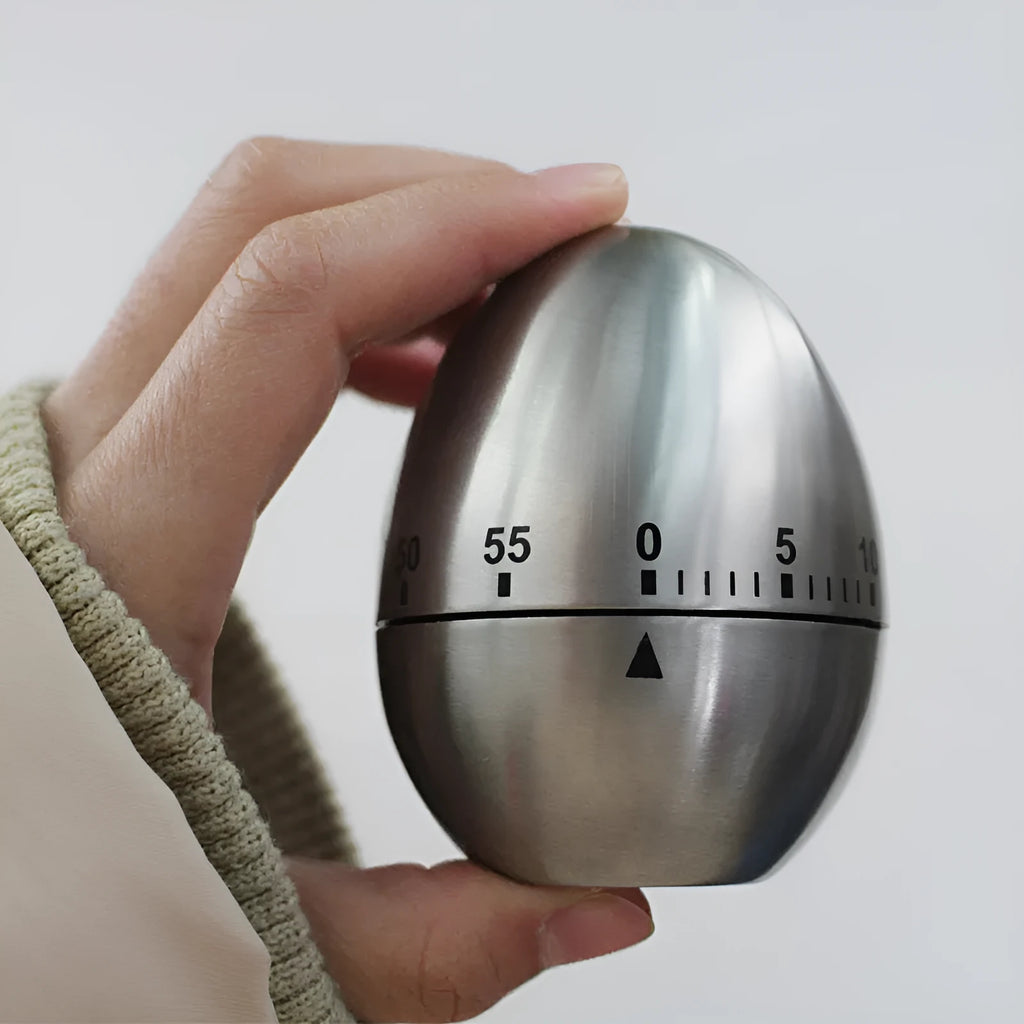 Stainless steel mechanical kitchen timer with egg shape design showing dial and measurement scale