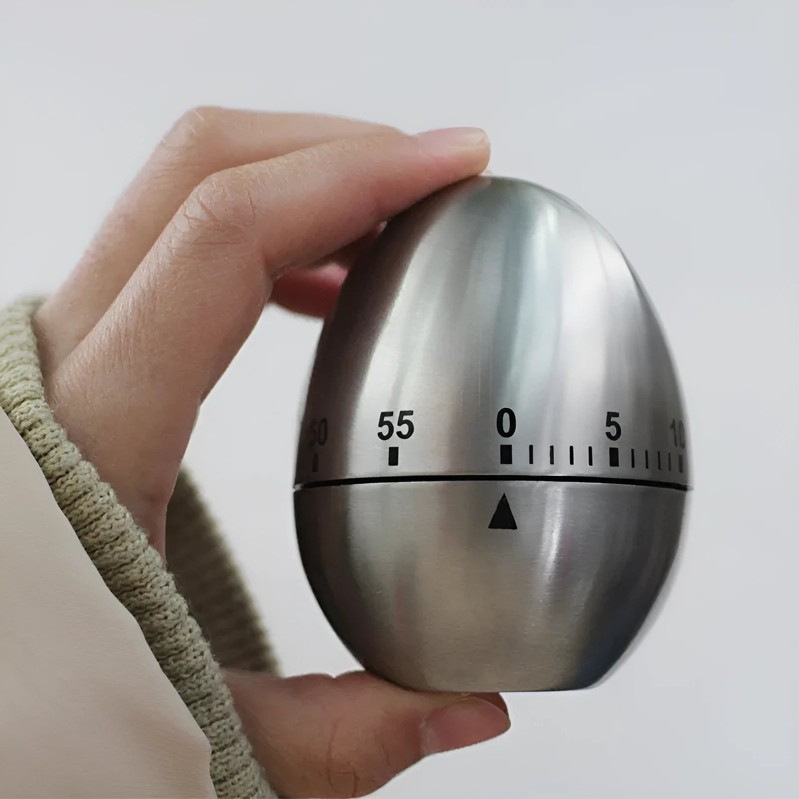 Stainless steel mechanical kitchen timer with egg shape design showing dial and measurement scale
