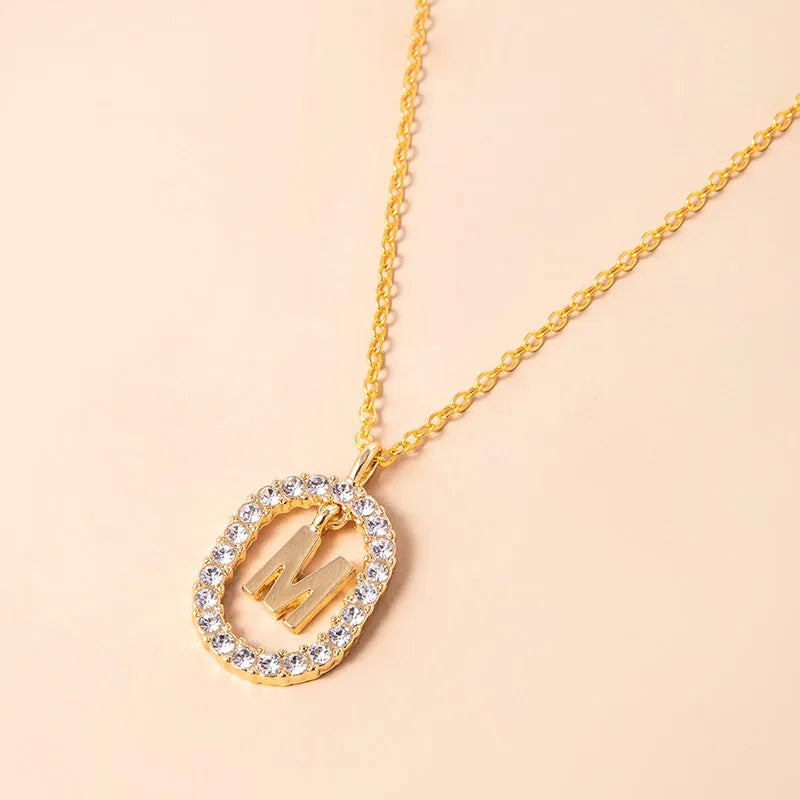 Gold crystal letter necklace with rhinestone initial on oval pendant and O-chain