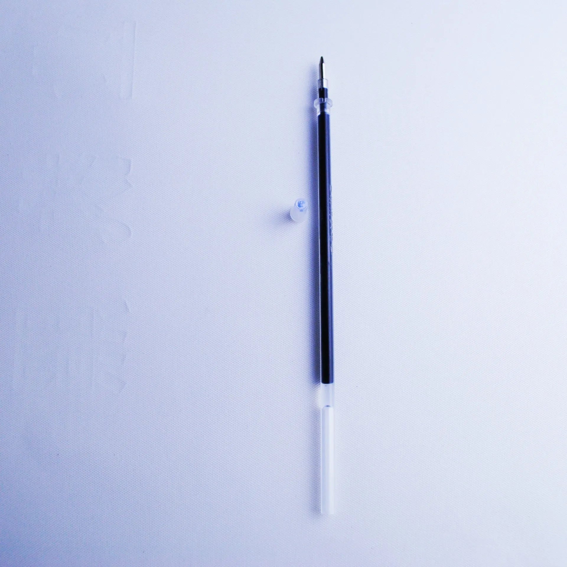 Portable plastic pen holder and eight 0.5mm blue ink refills on a white background.