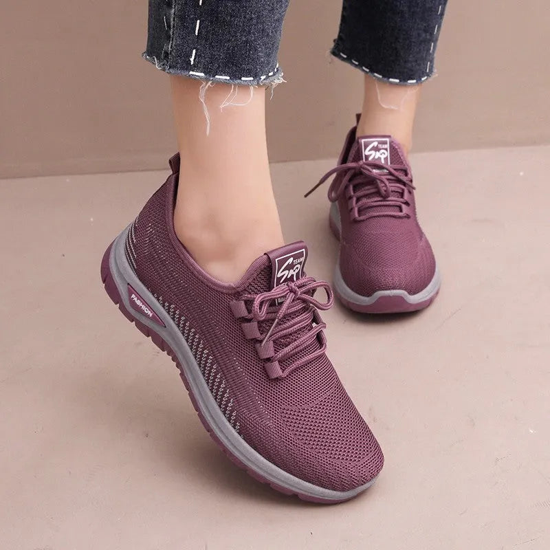 Women's black mesh sneakers with cross strap detail and round toe on a rubber sole.