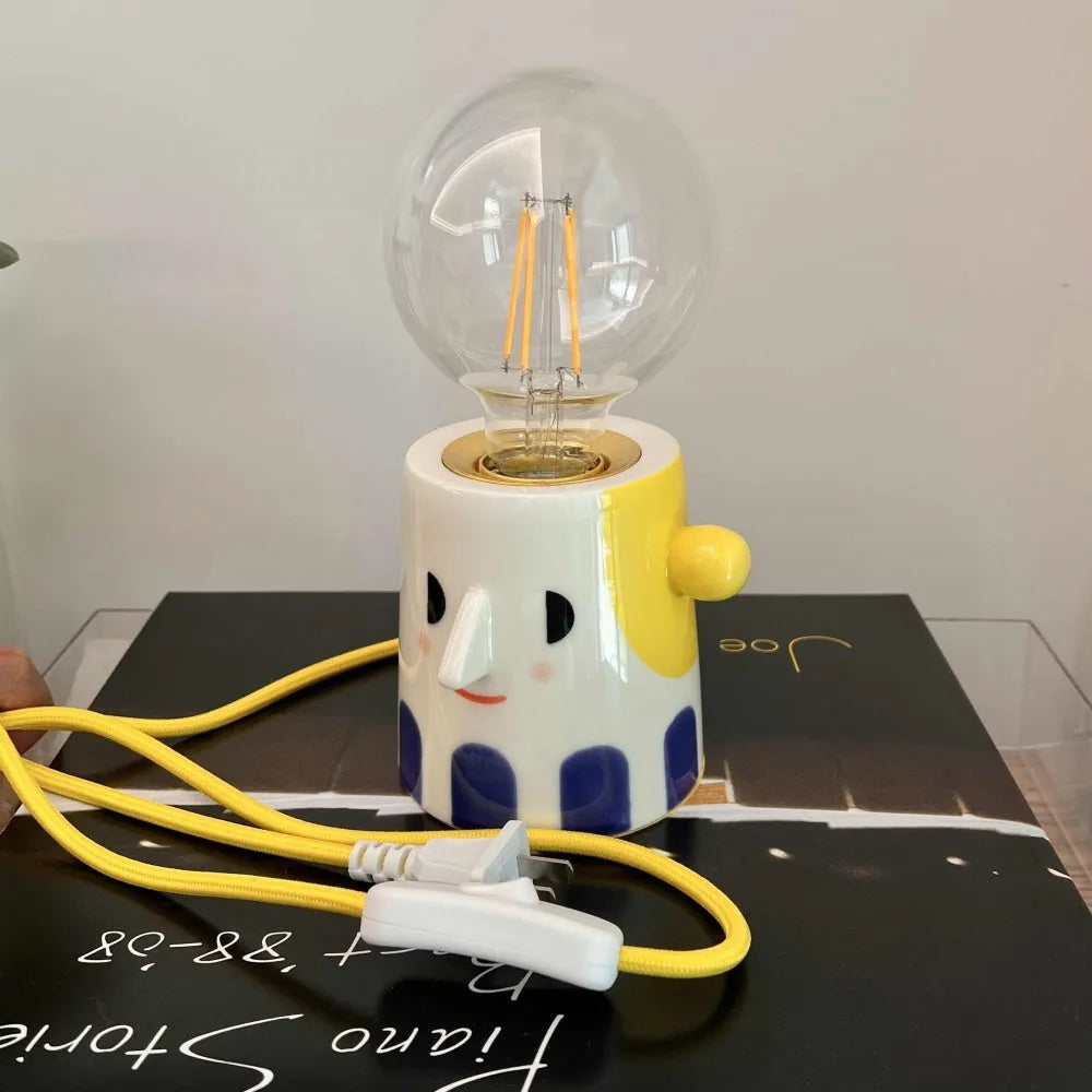 Handmade solid ceramic table lamp with spherical white shade on a wooden surface, showing UK plug.