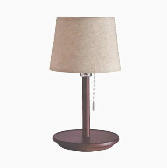 Walnut coloured solid wood bedside lamp with a white fabric lampshade and a cable switch
