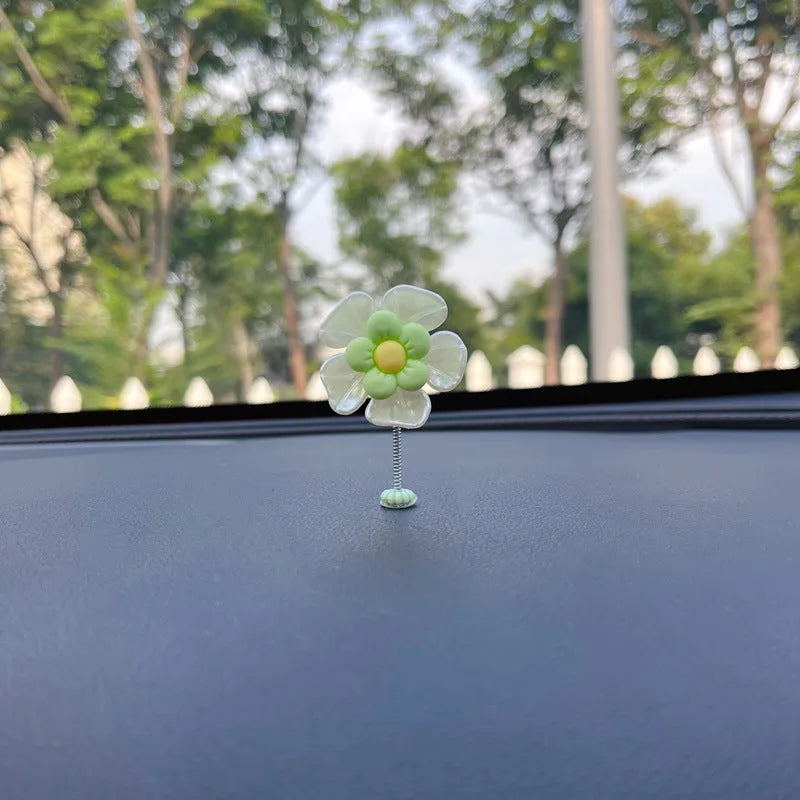 Small colourful plastic car decoration shaped like a swing, shown in blue, on a car dashboard.