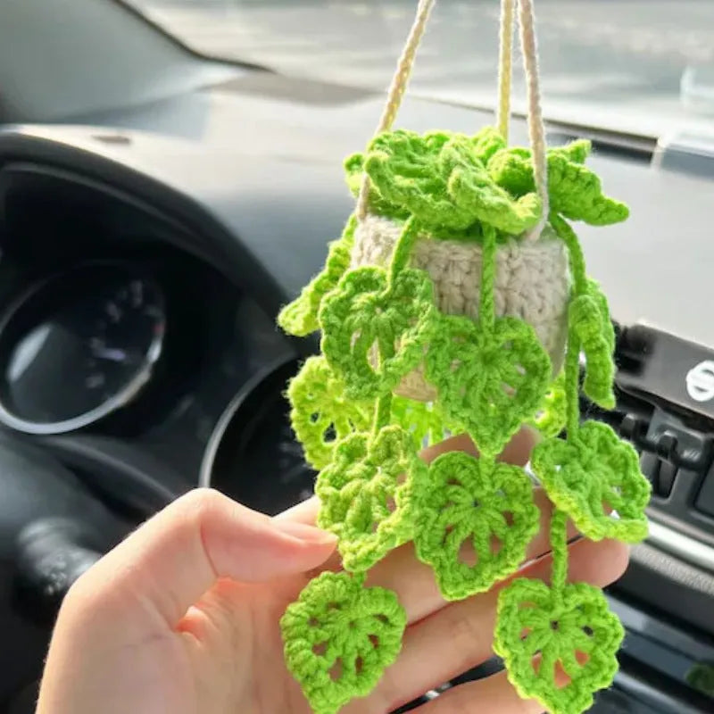Green and white crocheted wool car plant decoration with a white hanging rope.