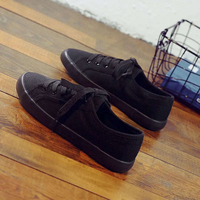 All black women's canvas lace-up work shoes with flat rubber sole on a white background.