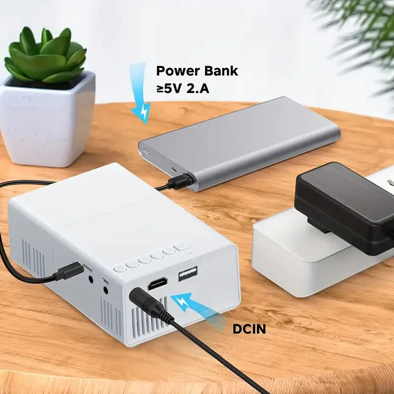 White and black M100 portable LED mini projector with remote control on a table.