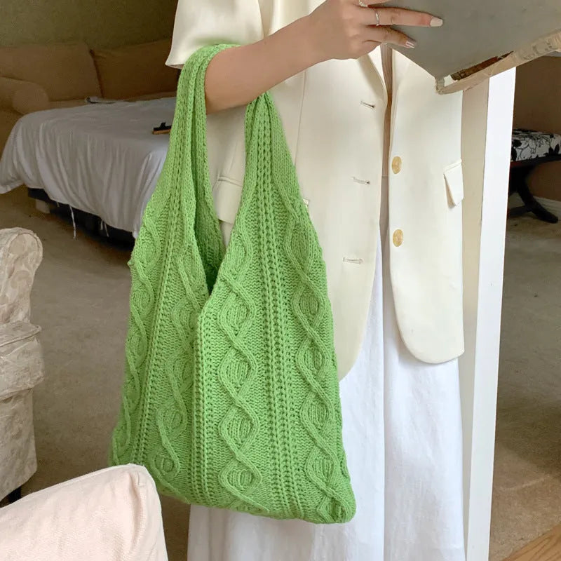 Light brown crochet knit tote bag with double shoulder straps on a wooden table.