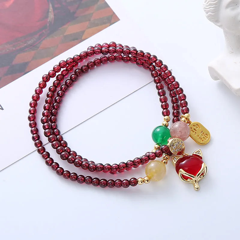 Purplish red adjustable rope bracelet with a detailed natural garnet fox charm.