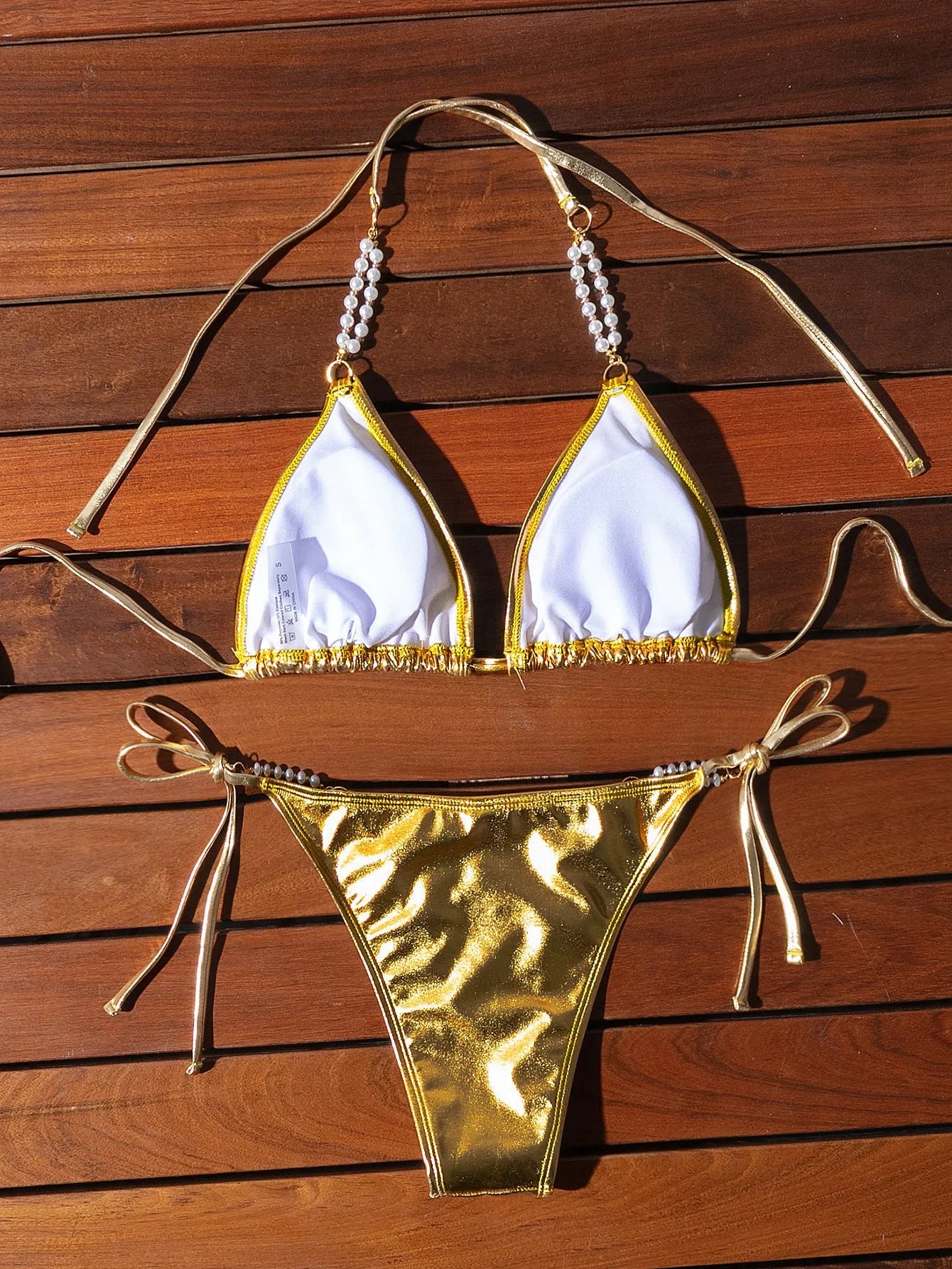 Gold halter lace-up bikini with pearl chain detail on mannequin showing front view