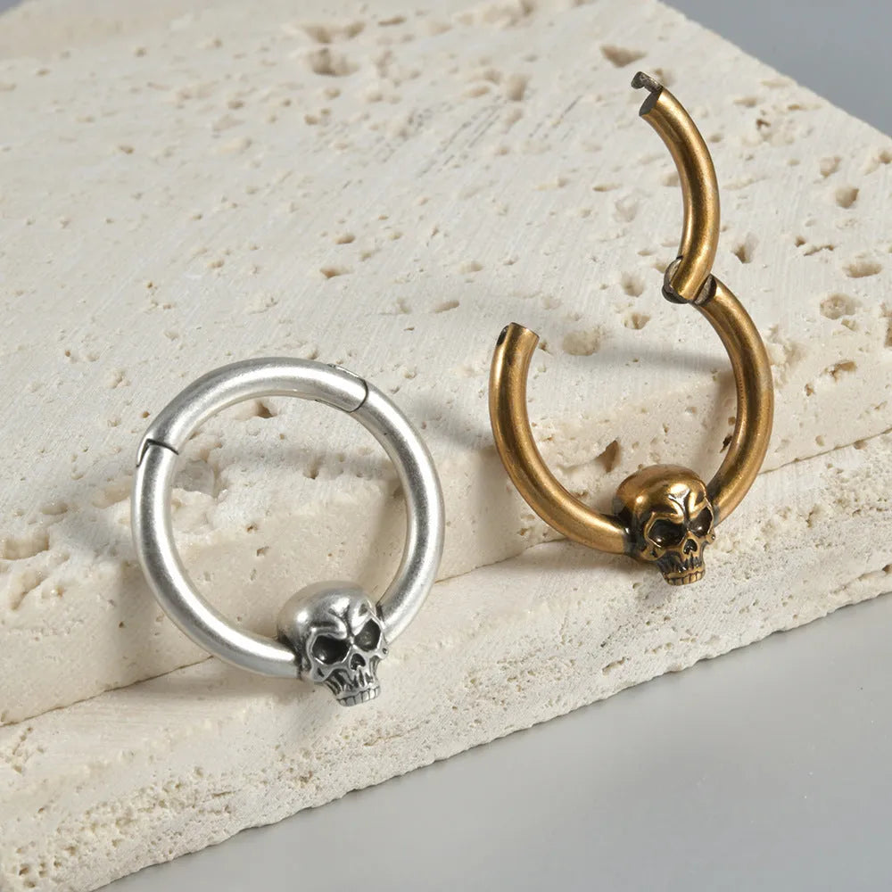 A pair of vintage-style copper earrings with an embossed ghost head design on a stud post, showing an antique silver finish.