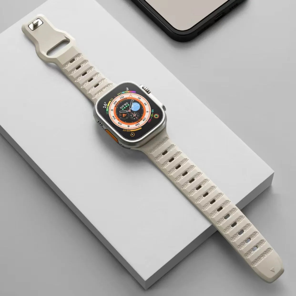 Fluoro rubber Apple Watch band with T-buckle in multiple colours on a grey background.
