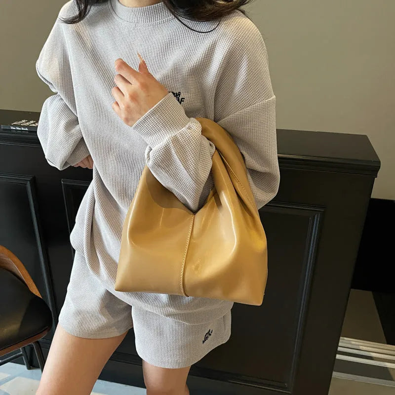 Casual dumpling shaped women's PU handbag in multiple colours showing phone compartment.