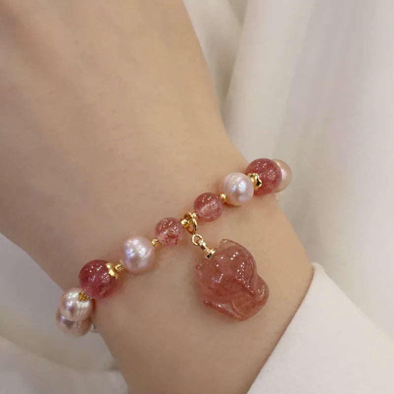 Women's light pink freshwater pearl and strawberry quartz bracelet with a silver fox charm on an adjustable chain.