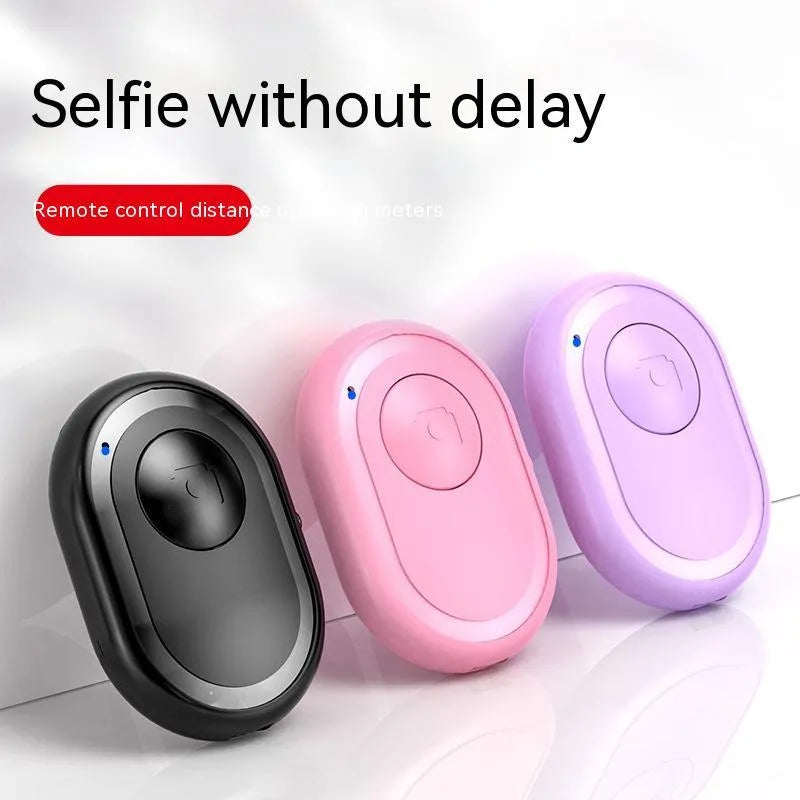 Wireless Bluetooth self-timer remote control in black, pink, and purple colours next to a smartphone.