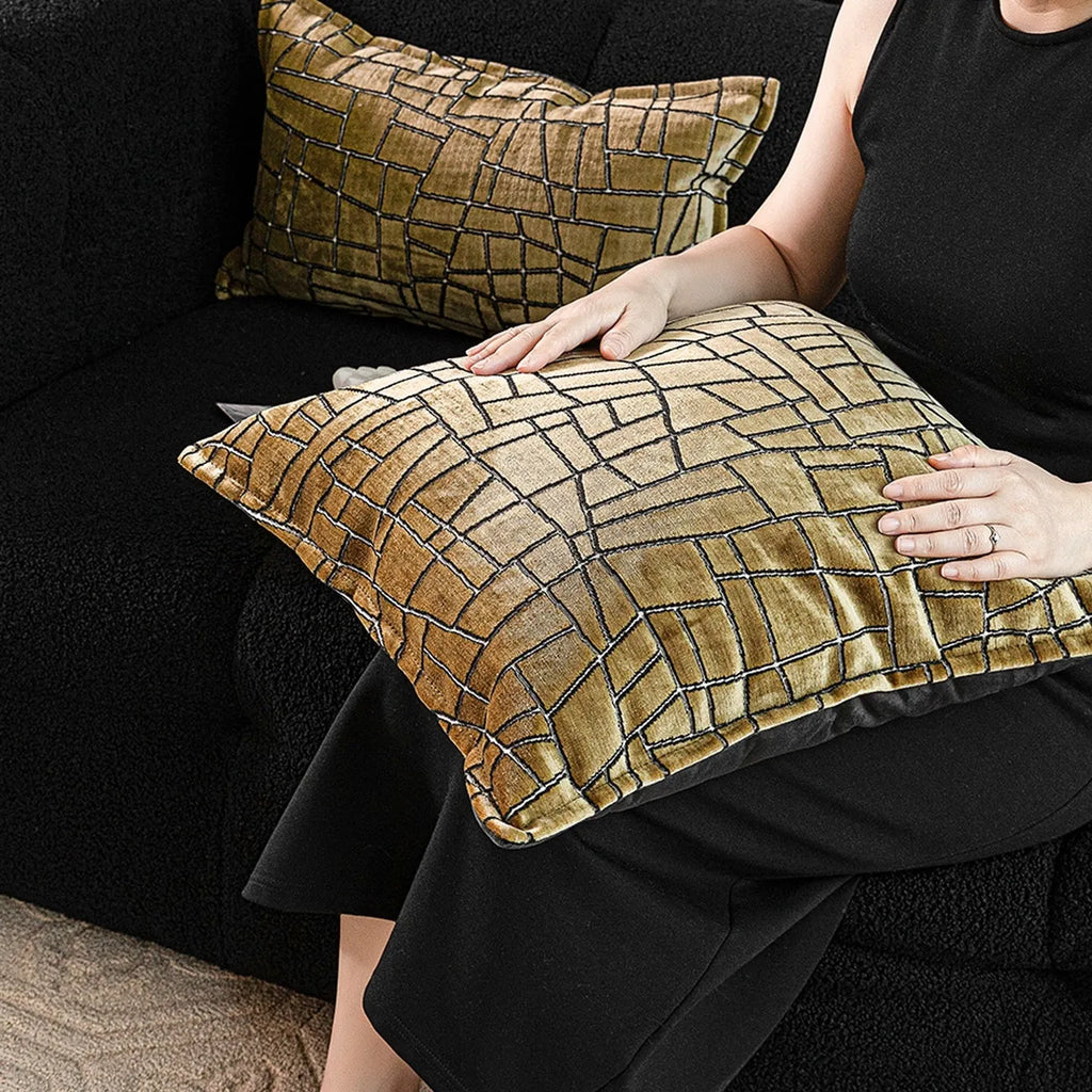 Geometric patterned cushion covers in gold colour on a grey sofa.