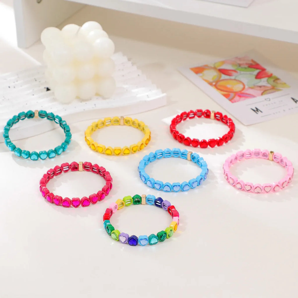 Colourful elastic bracelet with a shiny heart-shaped alloy charm on a stretch band.