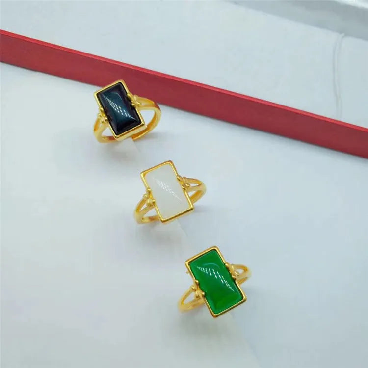 Close-up of an adjustable brass gold-plated ring with an electroplated finish and a green artificial gemstone inlay.