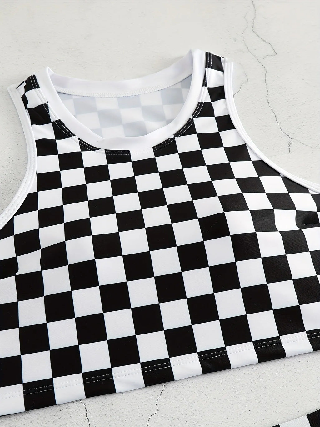 Adult female backless racing swimsuit with suspender straps in checkerboard print pattern