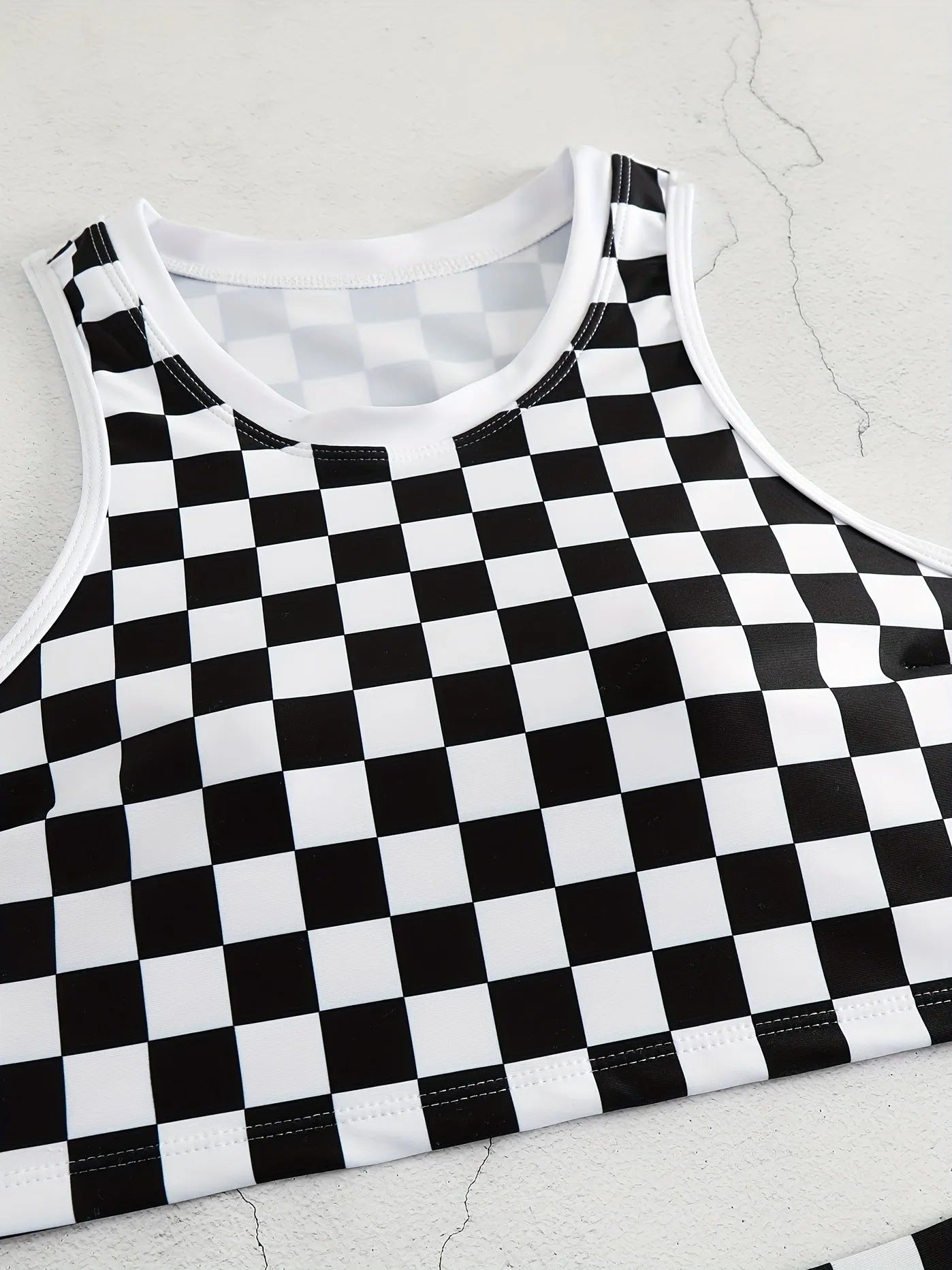 Adult female backless racing swimsuit with suspender straps in checkerboard print pattern