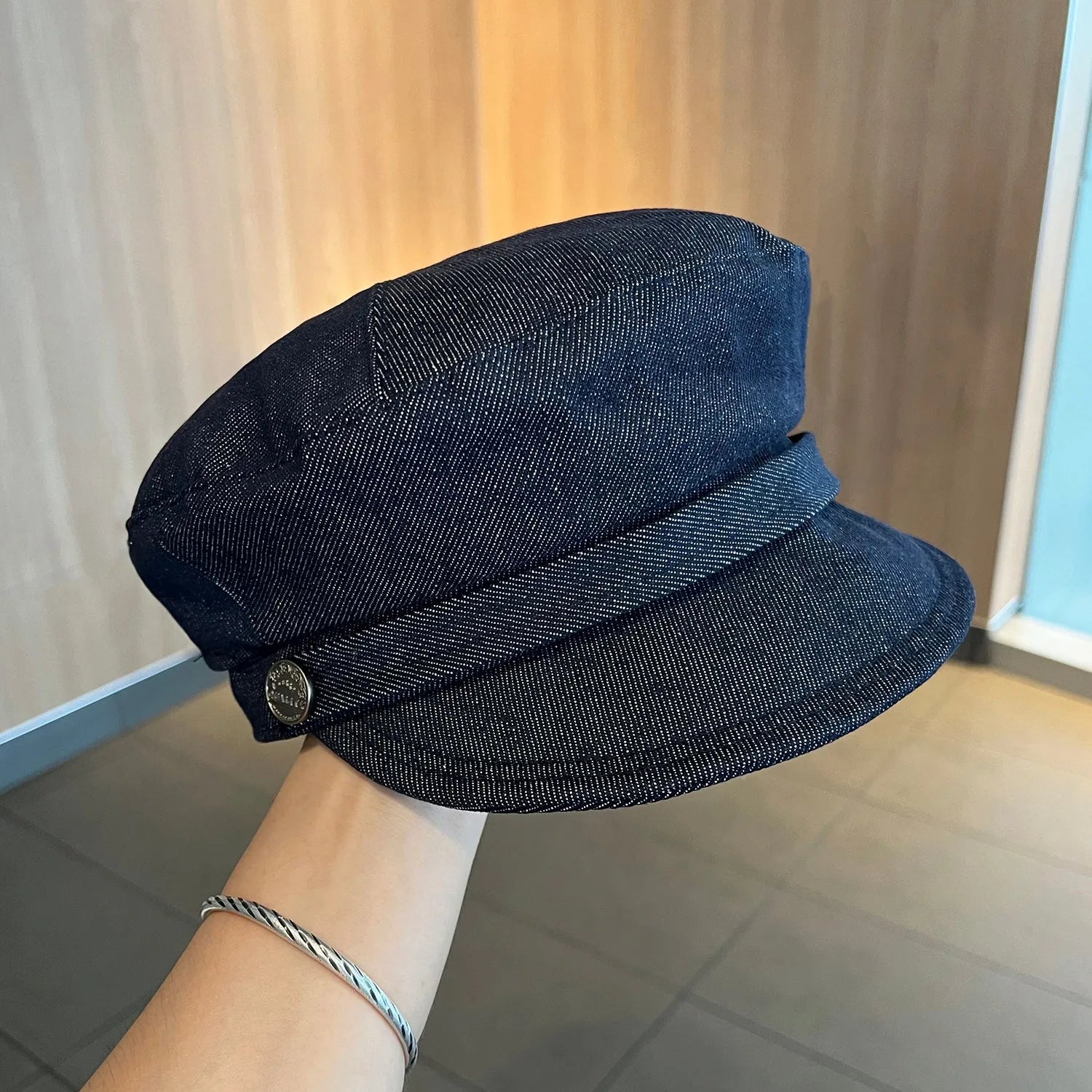 Dark blue denim octagonal newsboy flat cap with an adjustable strap, shown with a contrasting brown brim.