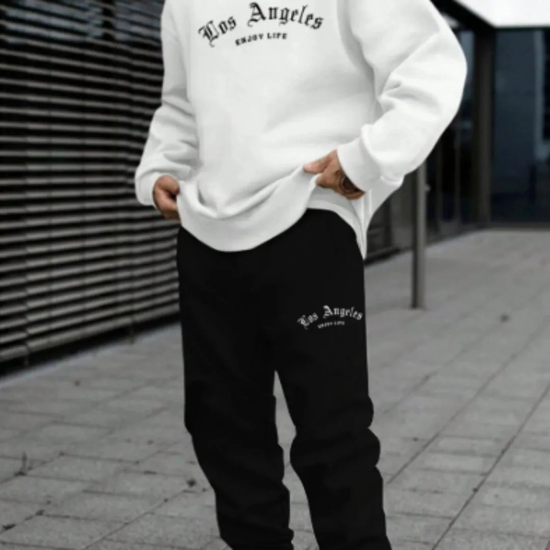 Man wearing a grey hooded pullover sweater and matching tracksuit bottoms from a winter sports leisure set.
