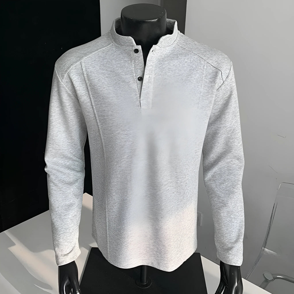 Man wearing a grey patchwork shoulder polo shirt with a stand-up collar and long sleeves.
