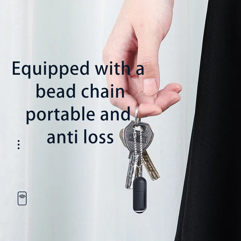 Small black capsule infrared emitter remote control for smartphones next to a phone.