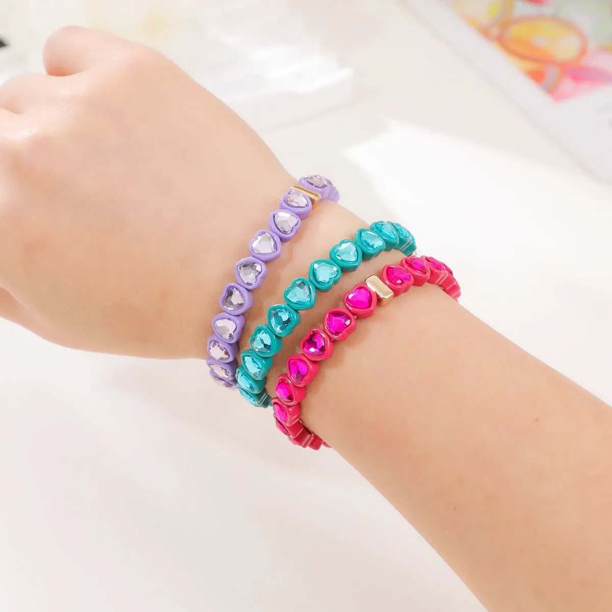 Colourful elastic bracelet with a shiny heart-shaped alloy charm on a stretch band.
