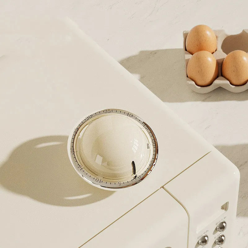 Mechanical kitchen timer in beige or black with manual twist dial and magnet backing, no battery required.