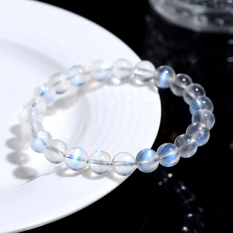 Polished natural cream body blue moonlight crystal bracelet on a wrist, showing simple bead design.