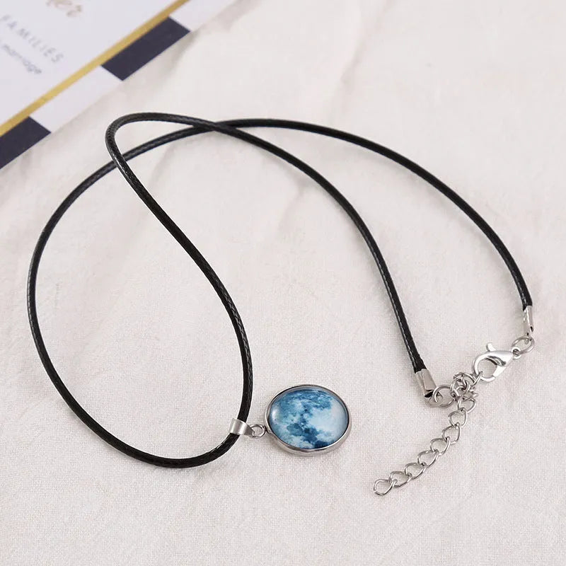 Close-up of a luminous alloy necklace with a glass pendant featuring a Christmas moon night sky and constellation design.
