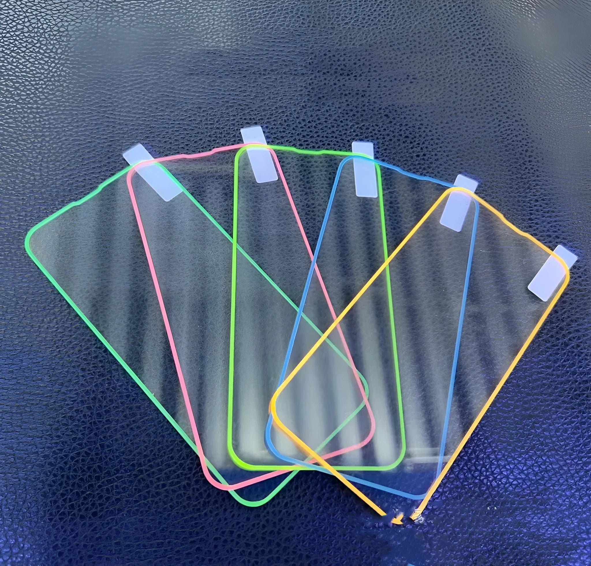 Fluorescent blue tempered glass screen protector glowing on an iPhone 13 in a dark setting.