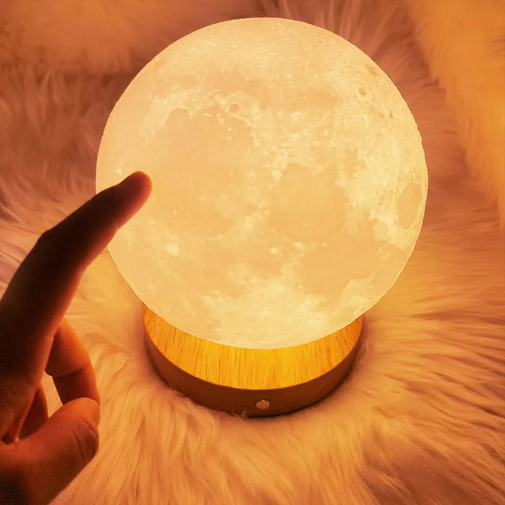 Rotating moon night light on wooden base showing three colour options and size scale