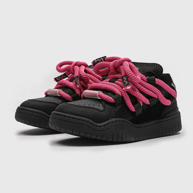 Pair of low-top unisex casual sneakers with thick flat rubber sole and lace-up front in a solid colour.