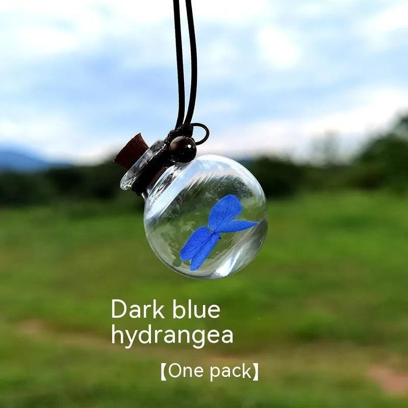 Glass car perfume pendant with preserved flowers inside, shown in a selection of different floral colours.