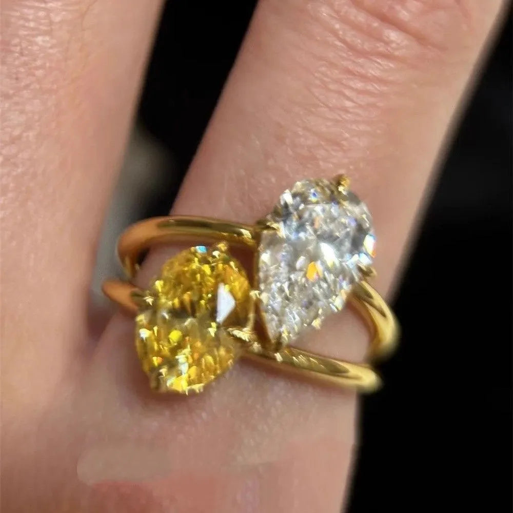 Geometric open-back silver ring with large central pear-cut clear zircon stone on a model's hand.