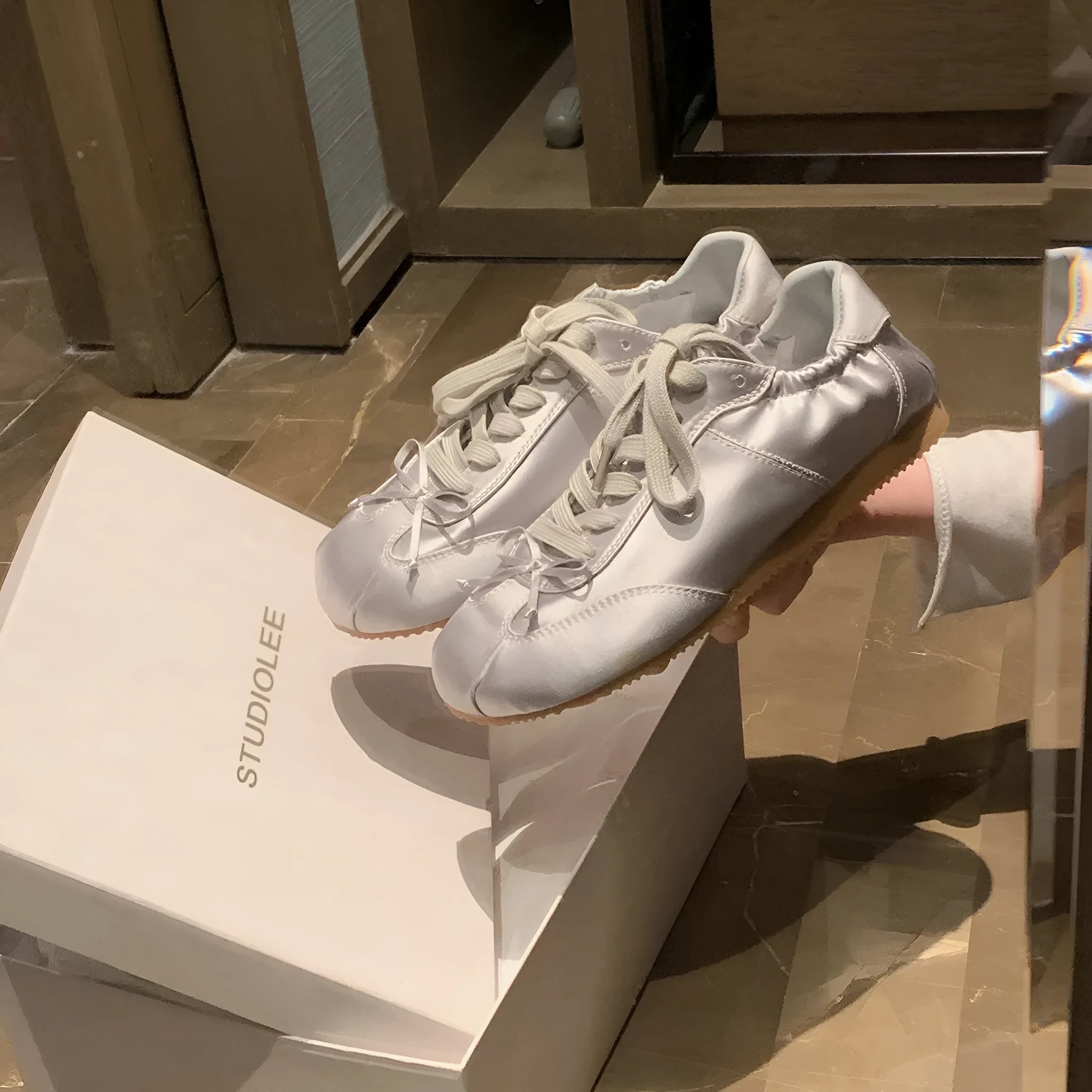 Women's champagne pink satin ballet flat shoes with a round toe and white front lace-up detail.