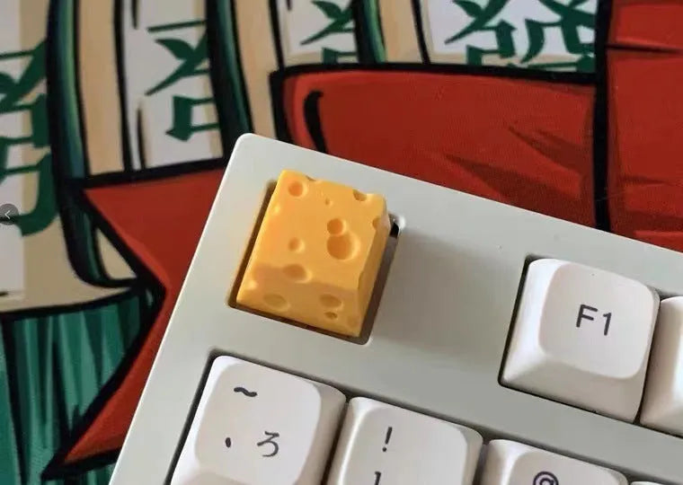 Yellow resin cheese-shaped key cap for mechanical keyboards, shown from a top-down angle.