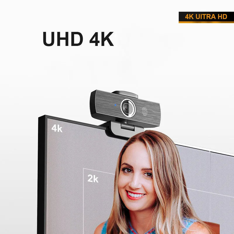 Black USB computer webcam with magnetic privacy cover on a desk next to a laptop.