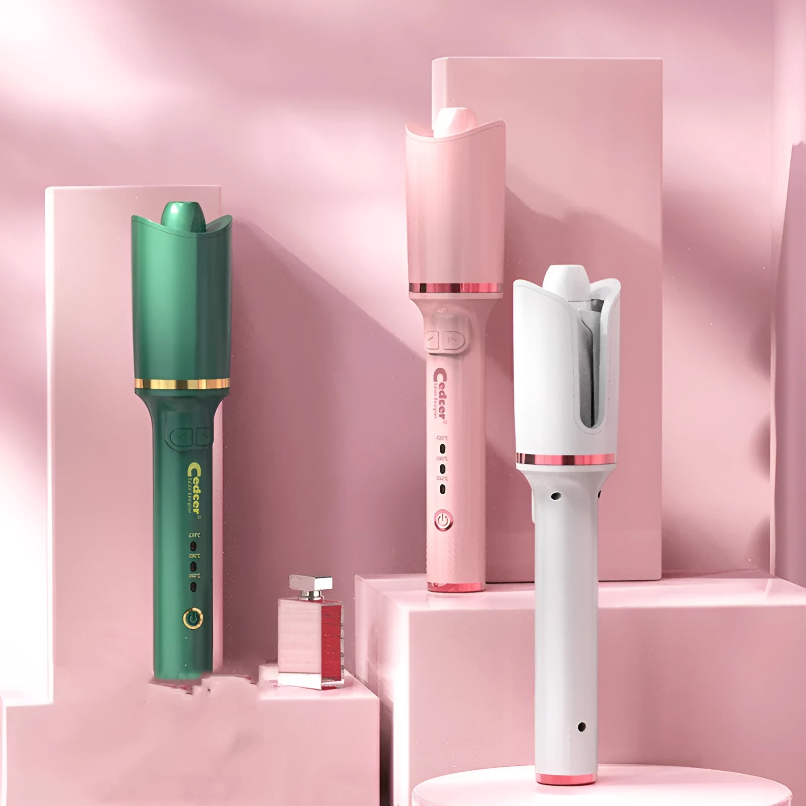 Electric rotating hair curler with tourmaline ceramic barrel in green, pink, and matte white on a neutral background