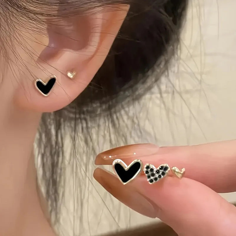 Three pairs of heart-shaped alloy earrings in gold, black, pink, and black-white colours