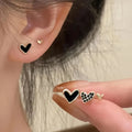 Three pairs of heart-shaped alloy earrings in gold, black, pink, and black-white colours