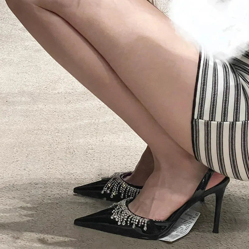 Black high heel sandals with rhinestone tassel decoration, pointed toe, and slingback strap showing 10cm stiletto heel