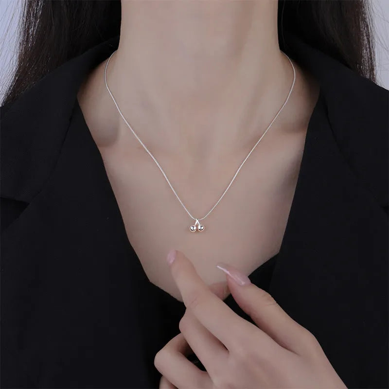 Close-up of a silver cherry pendant necklace on a textured snake bone chain, adjustable from 21cm to 50cm.